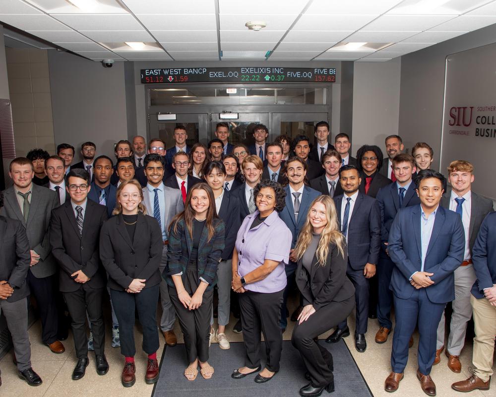 students in Rehn lobby with stocks in background